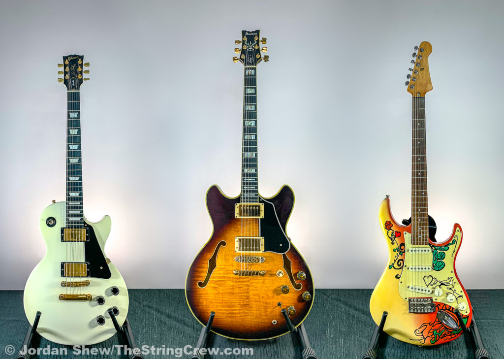 three electric guitars standing beside one another with white background.